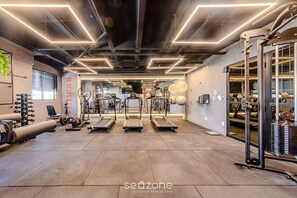 Ein modernes Fitnessstudio mit Laufbändern, Kraftgeräten und einer Spiegelwand.