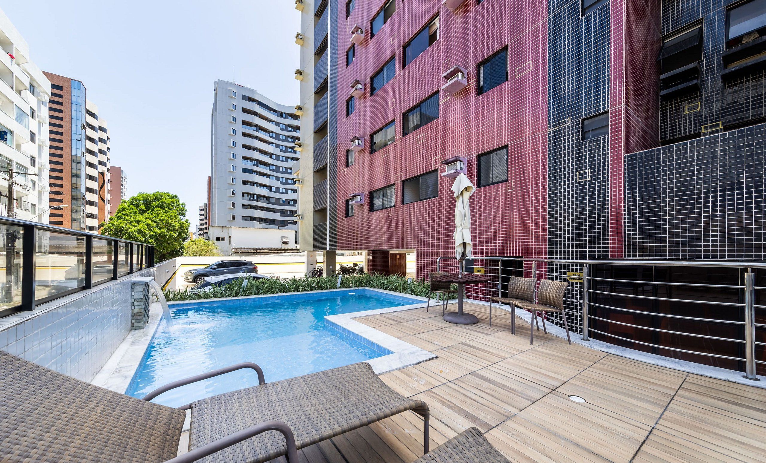 Área de piscina en la azotea con sillas de descanso y vistas a edificios cercanos.