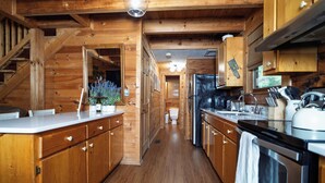 A wooden cabin-style kitchen with a central island, built-in appliances, and a staircase leading to an upper level.