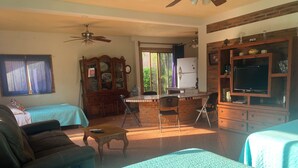 A room with a bed, a sofa, a desk with a computer, a television, and a ceiling fan. - La Brisa - Large Studio Suite (Punta de Mita)