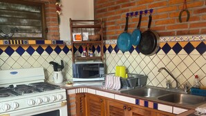 A kitchen with a stove, oven, microwave, sink, and hanging pots. - La Brisa - Large Studio Suite (Punta de Mita)