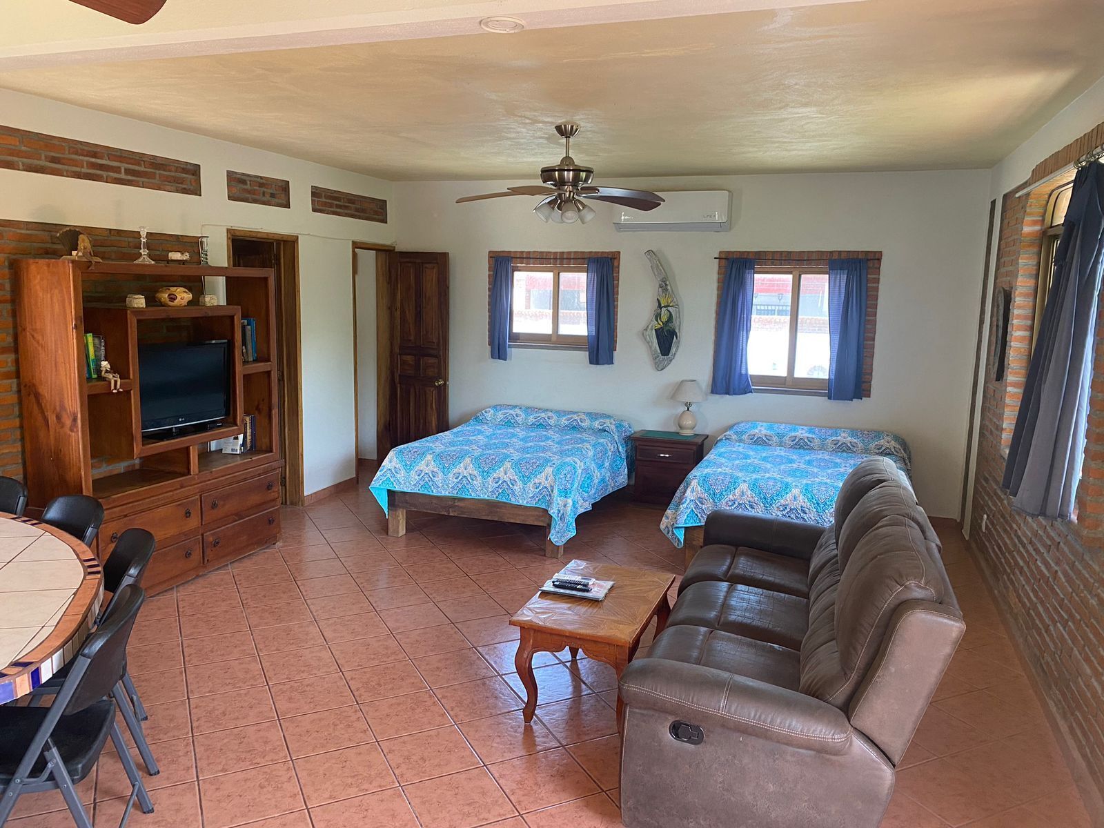 Una habitación con dos camas, un sofá, un televisor y una mesa de comedor.