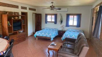 Una habitación con dos camas, un sofá, un televisor y una mesa de comedor.