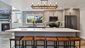 A modern kitchen with a large island, stainless steel appliances, and a stone backsplash. - Powder Pointe by Avantstay Minutes From Base Village (Park City)