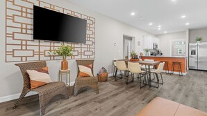 Una cocina moderna con horno empotrado, refrigerador y comedor con mesa y sillas.