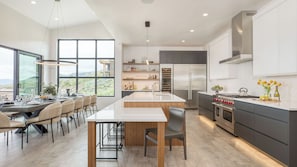 A modern kitchen with a central island, built-in appliances, and a dining area with a view.