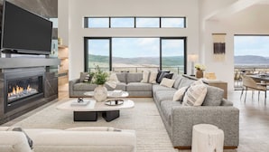 Un salón espacioso con chimenea, ventanas amplias y vistas al paisaje.