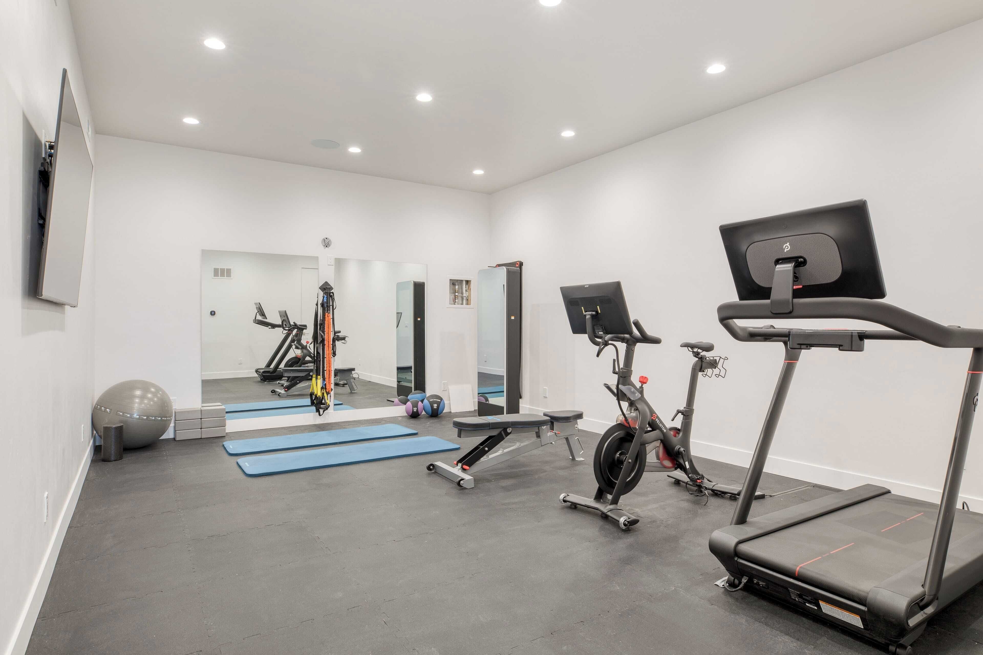 A modern gym with treadmills, stationary bikes, and exercise balls.