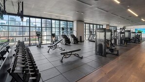 A modern gym with various exercise equipment, large windows, and a city view. - NEW 2BD/2BR  WorldCenter Miami - Amazing views (Miami)