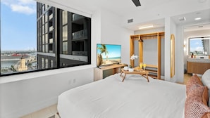 A modern hotel room with a large bed, a television, a wooden side table with breakfast items, a large window with a city view, and a ceiling fan. - NEW 2BD/2BR  WorldCenter Miami - Amazing views (Miami)