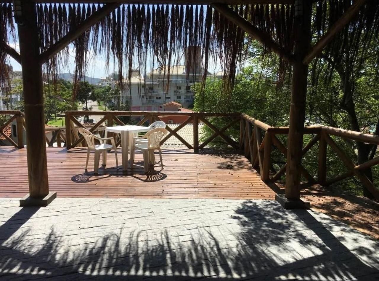 An outdoor wooden deck with a table and chairs, surrounded by a wooden fence and trees.