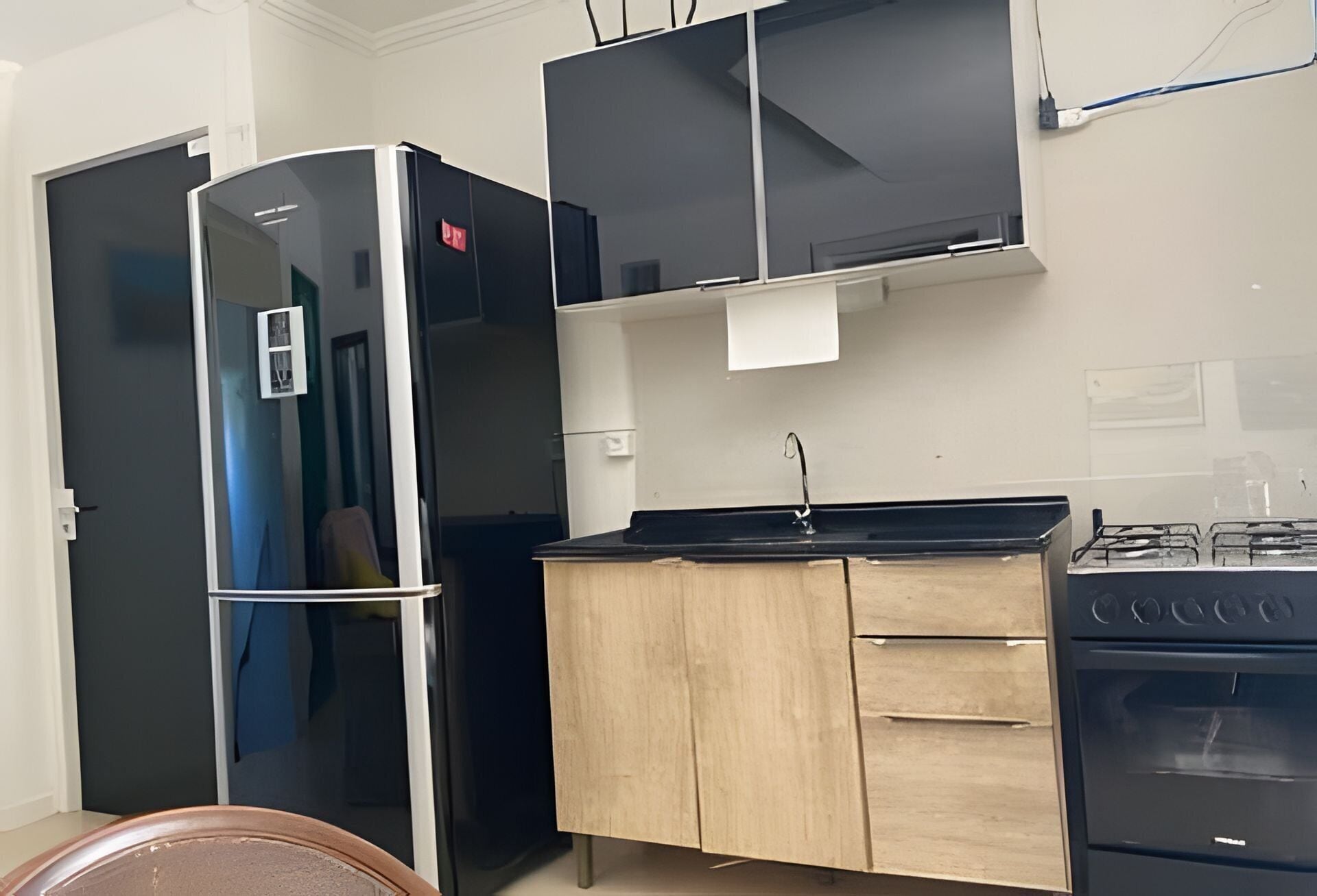 Una cocina compacta equipada con refrigerador, microondas, estufa y alacenas de madera.