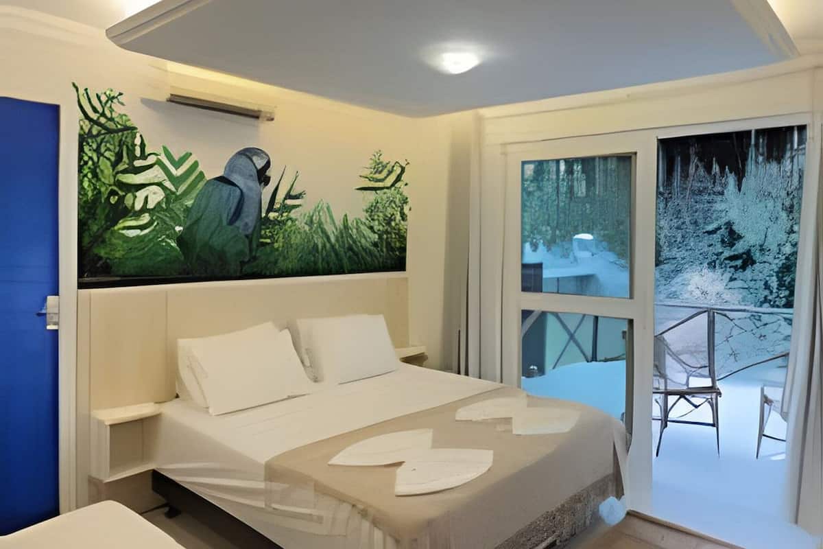 A bedroom with a bed, a smaller bed or sofa, a painting, and a view of a snowy outdoor area.