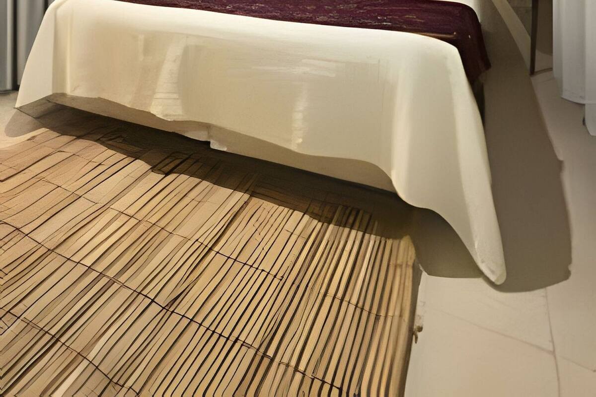 A modern bedroom with a large bed, a small window, and a ceiling light.