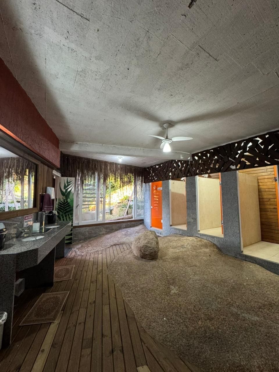 A bathroom with a wooden floor, a sink, a mirror, and a ceiling fan.