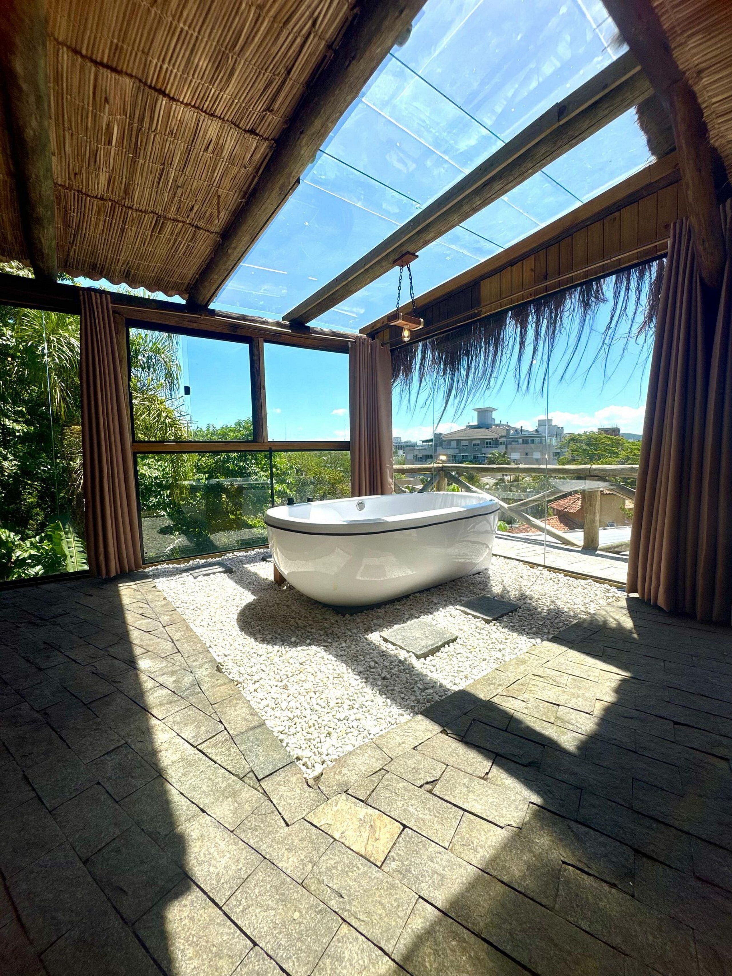 A modern bathroom with a freestanding bathtub, large windows, and a view of a cityscape.