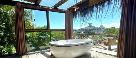 A modern bathroom with a freestanding bathtub, large windows, and a view of a cityscape.