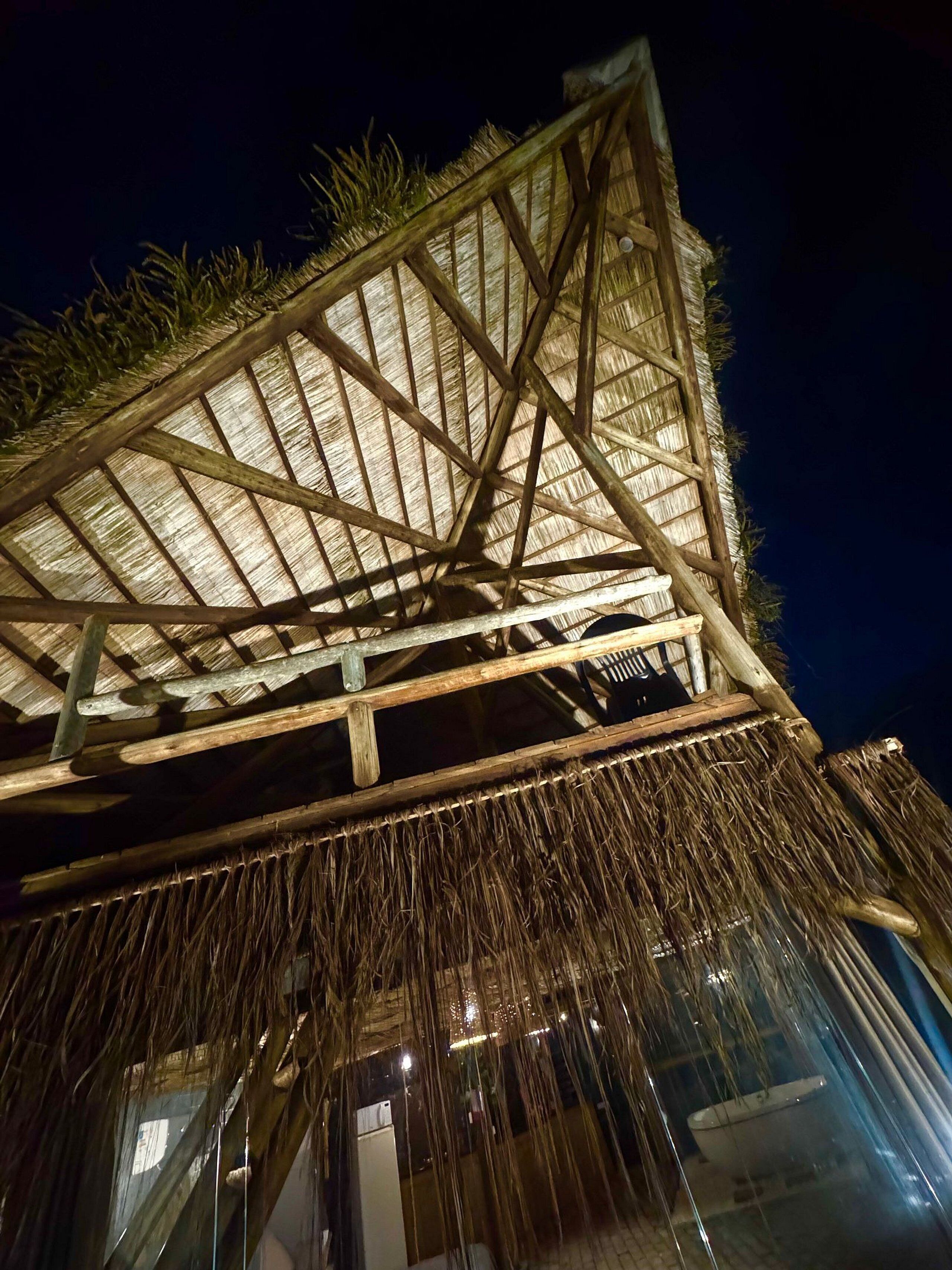 Una estructura de techo de paja con armazón de madera, probablemente parte de un edificio o una construcción separada.