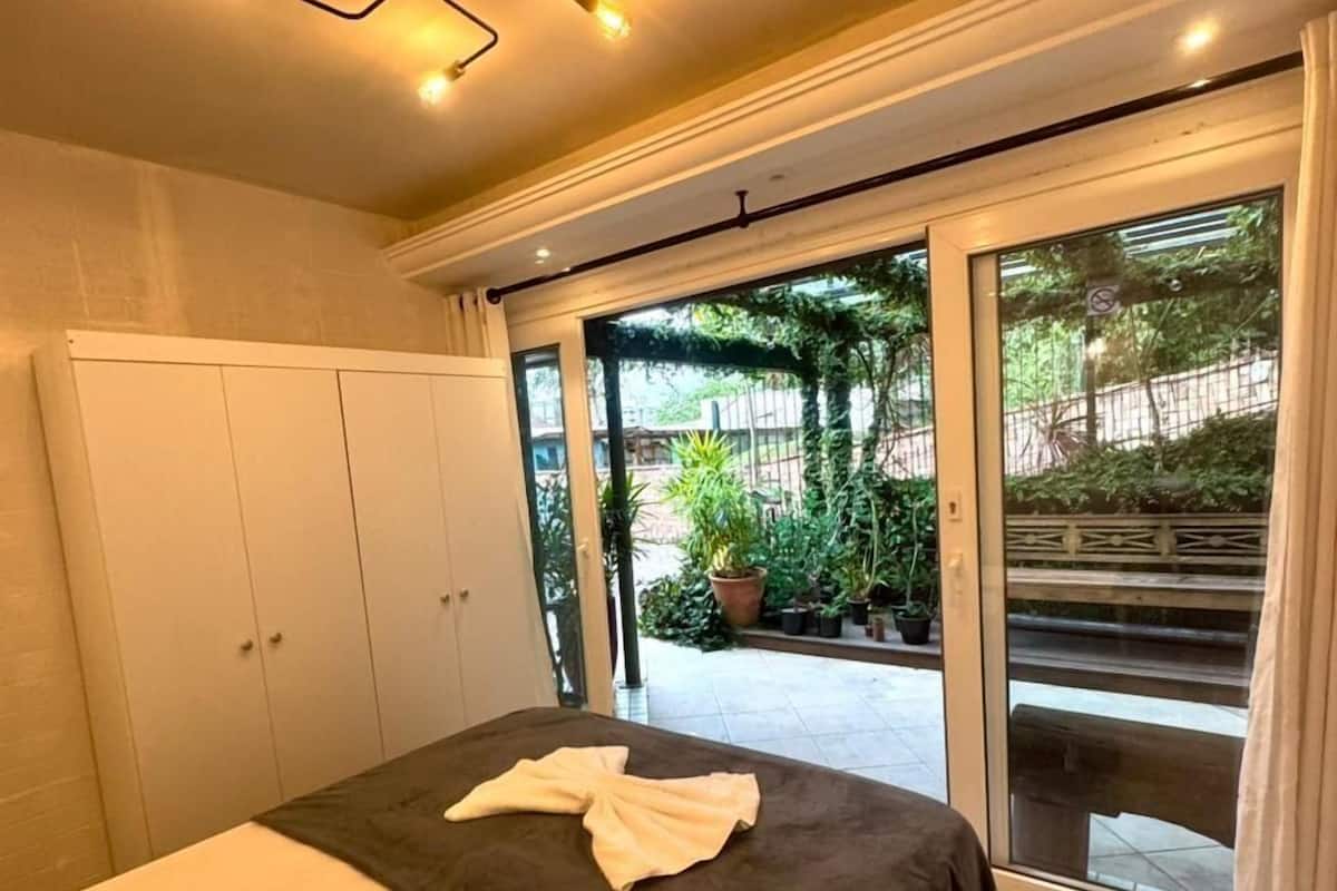 A bedroom with a bed, a wardrobe, and a view of the outside.