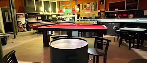 Zona de bar moderna con una isla central, taburetes y luminarias colgantes.