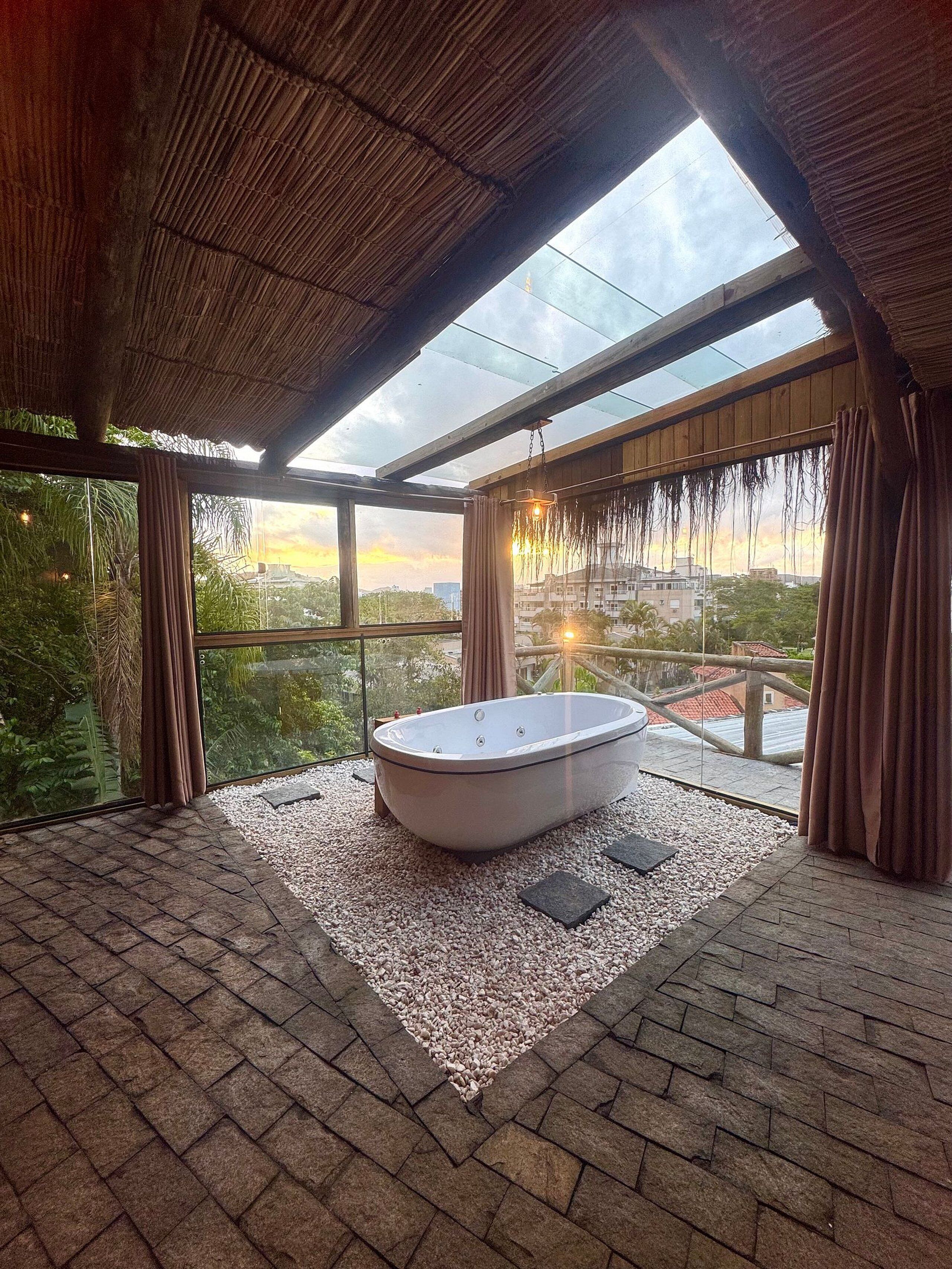 Un baño moderno con una bañera independiente, ventanas amplias y vistas a la ciudad.