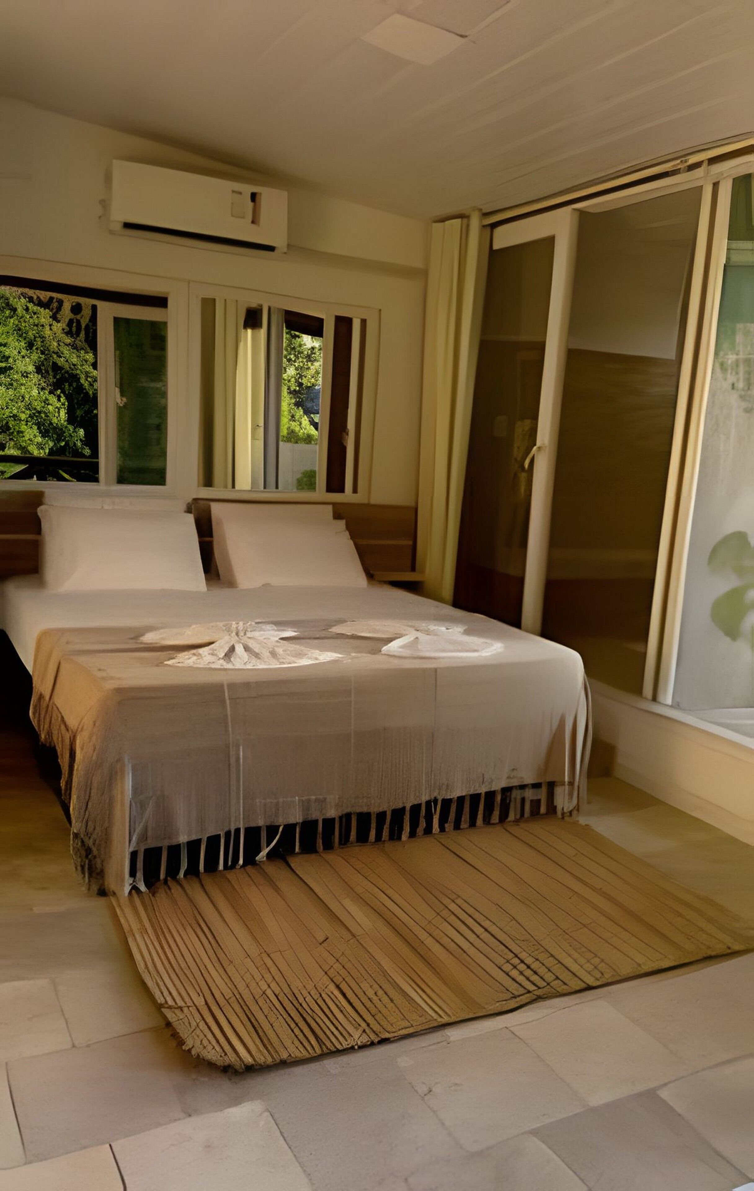 A bedroom with a bed, a large window, and a sliding glass door.