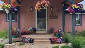 A building with a wooden facade, a welcoming sign, and flower arrangements. - Adventure Awaits 16 Private Acres secluded getaway in the beautiful Black Hills (Lead)