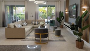 A modern living room with a sofa, coffee table, and TV. - Spectacular 9BR Villa Your Dream (Kissimmee)