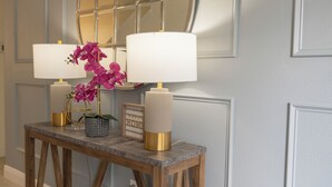 A wooden console table with two lamps and a mirror against a wall with paneling. - Spectacular 9BR Villa Your Dream (Kissimmee)