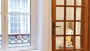 A room with a wooden door, a window with a view of a balcony, and a radiator. - Calm apt /60m2/near Notre-Dame and Seine/2bdrs (Paris)