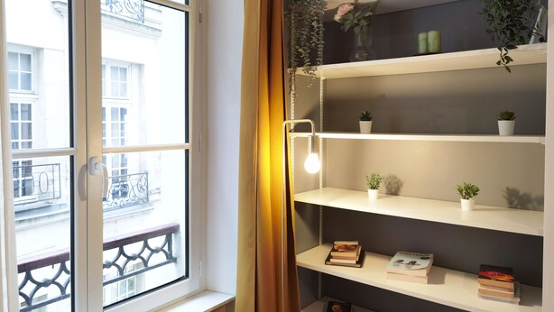 A room with a window, a door, and a shelf with books and plants. - Calm apt /60m2/near Notre-Dame and Seine/2bdrs (Paris)