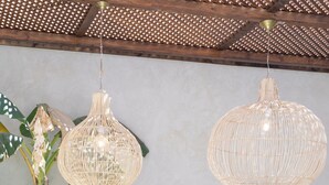 A dining area with a rustic table, hanging wicker lamps, and a potted plant. - Riad Lamalika (Marrakech)