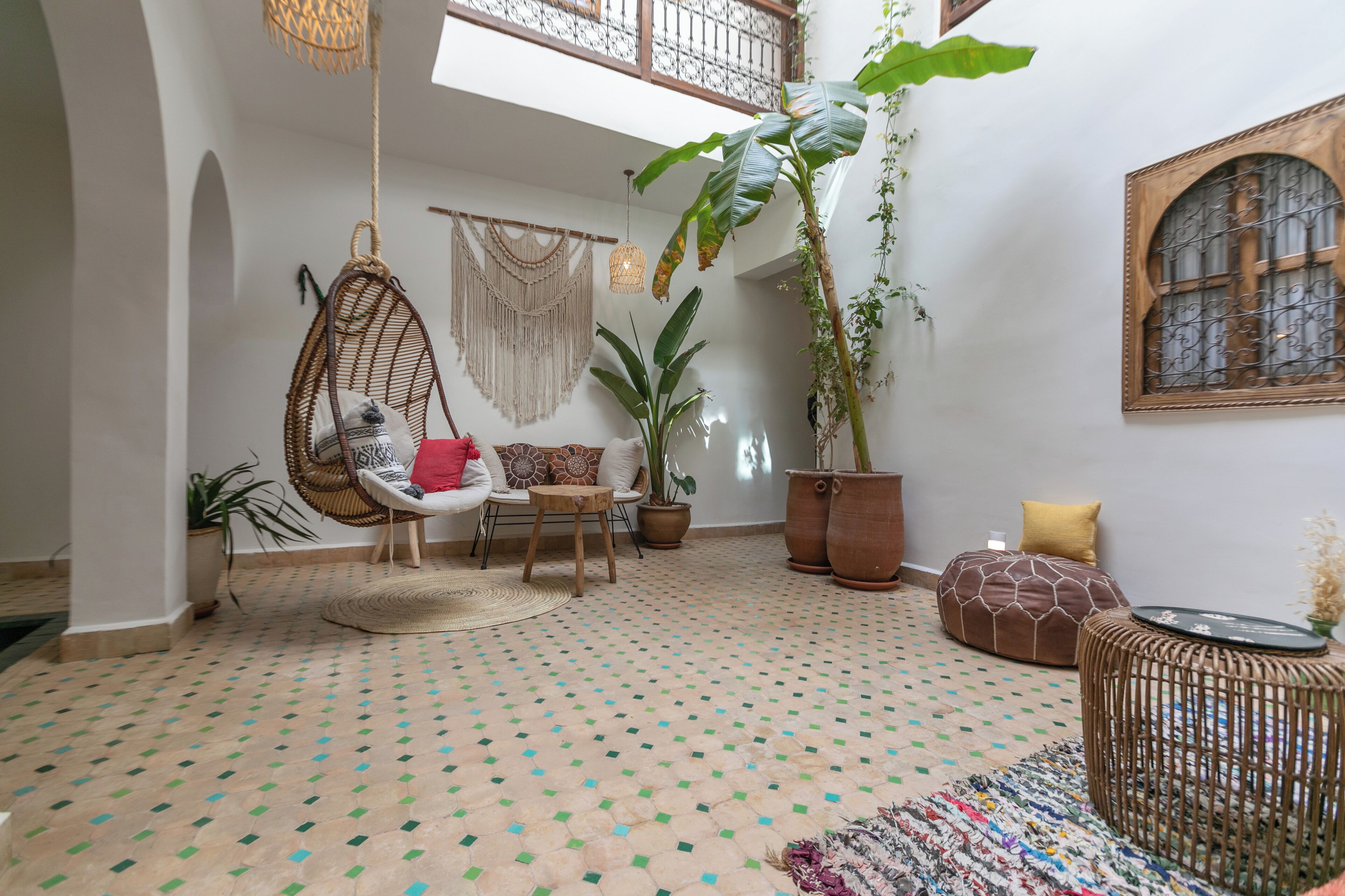 A cozy interior with a hanging chair, a round table, and a potted plant.