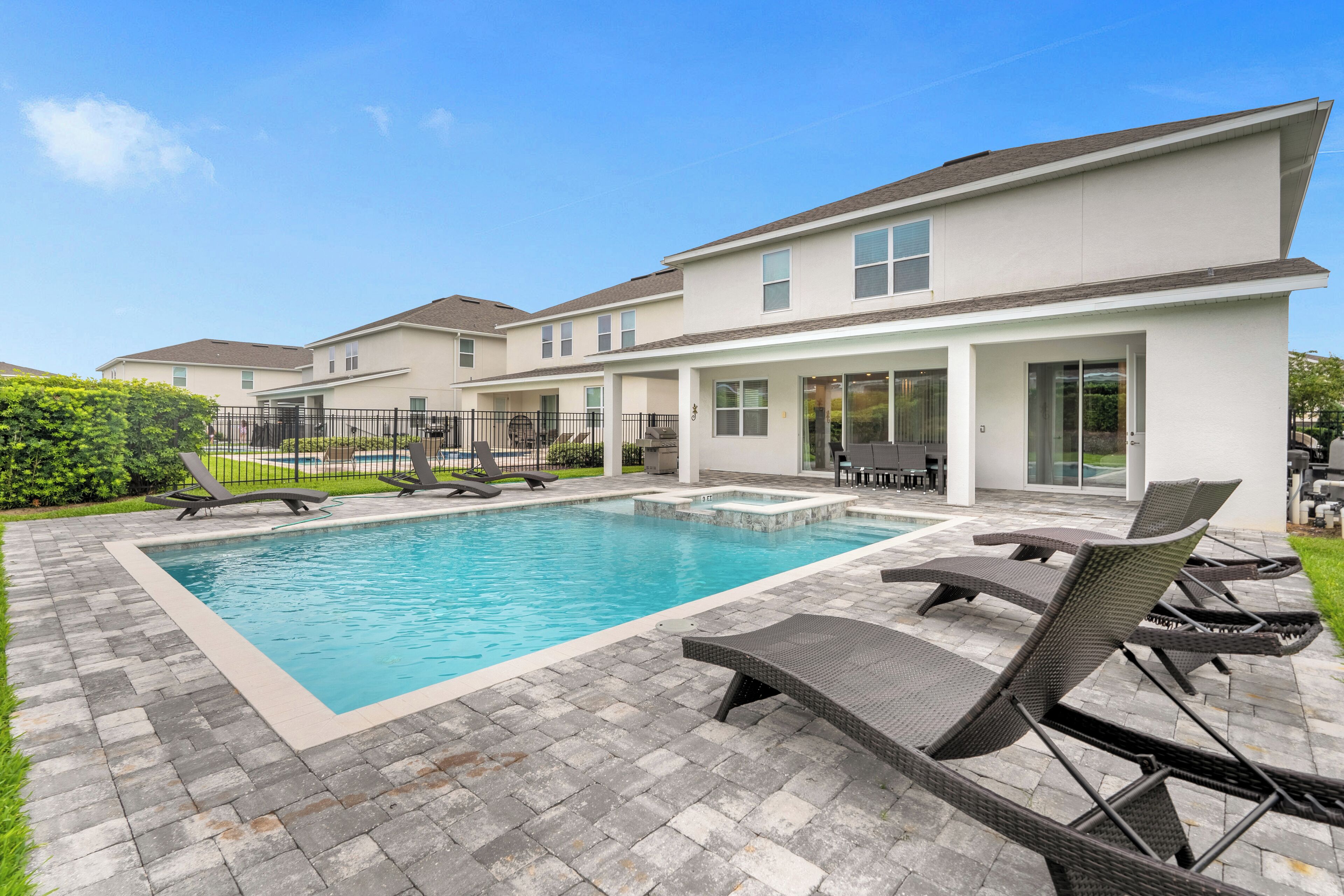 A modern residential building with a swimming pool, outdoor seating, and a well-maintained garden.