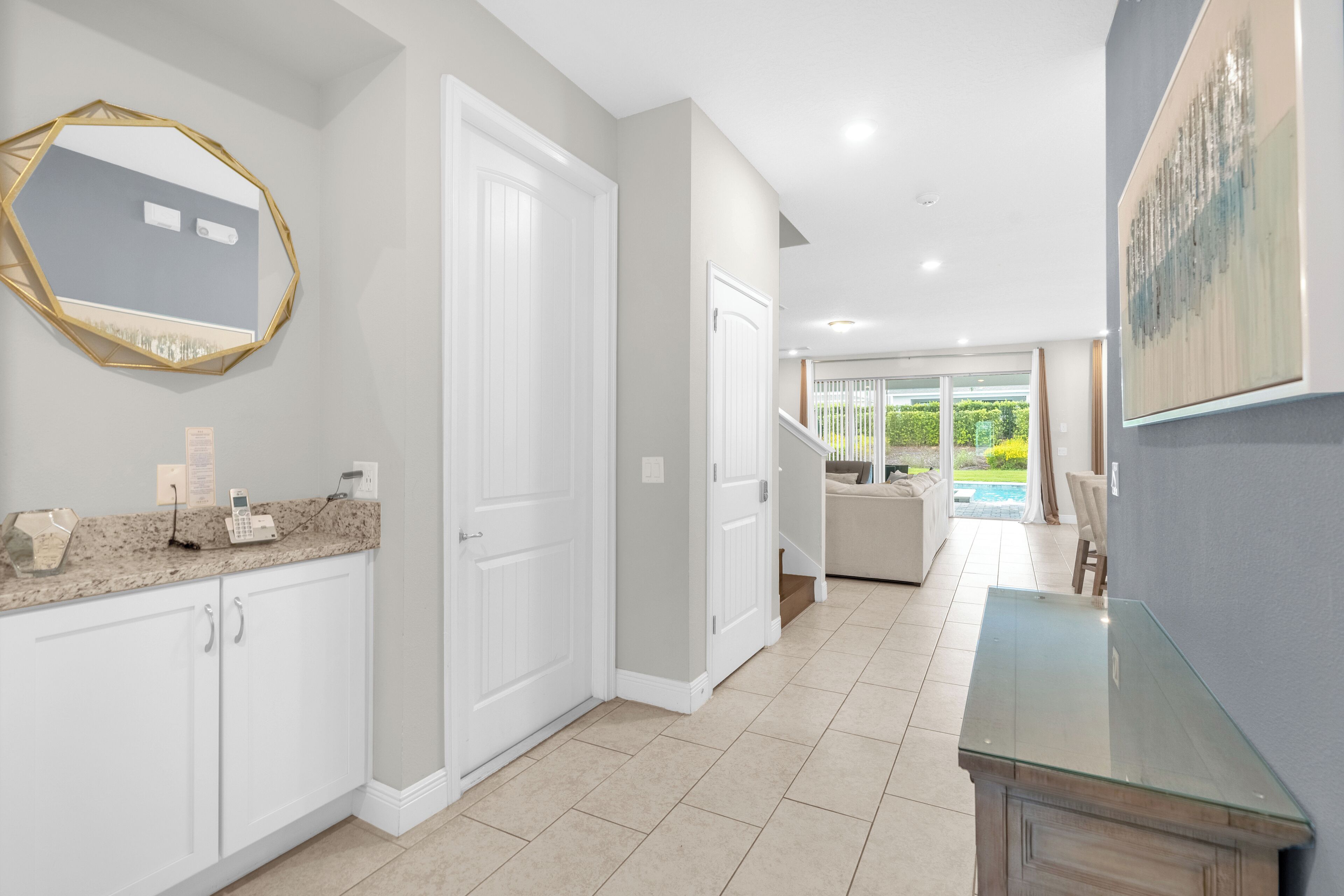 A modern kitchen with white cabinets, a granite countertop, and a glass-top dining table.