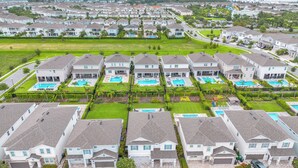 Una zona residencial con varias casas, cada una con jardín delantero y piscina.