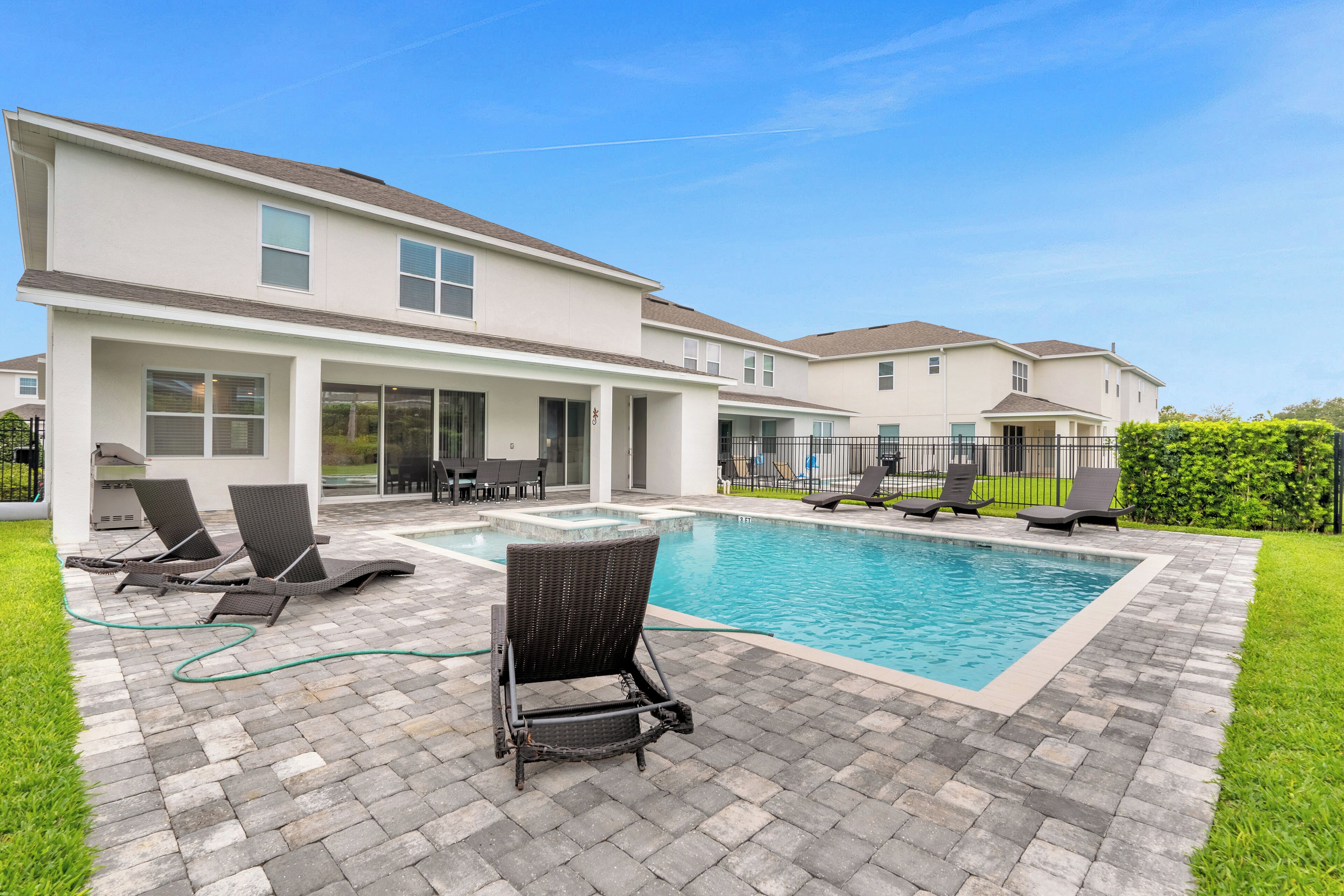 A modern two-story house with a swimming pool, outdoor seating, and a well-maintained lawn.