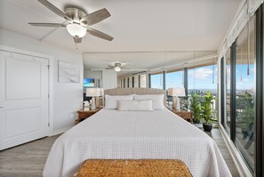 Una camera da letto con un letto grande, due comodini, una ventola a soffitto e vista sulla città.