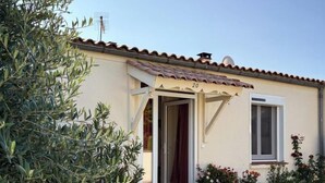 Una casa con techo de tejas, una puerta y un ventanal. Un camino de grava conduce a la puerta.