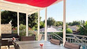 Un porche cubierto con una mesa y sillas, una piscina al fondo y un logotipo con "Gîtes de France".