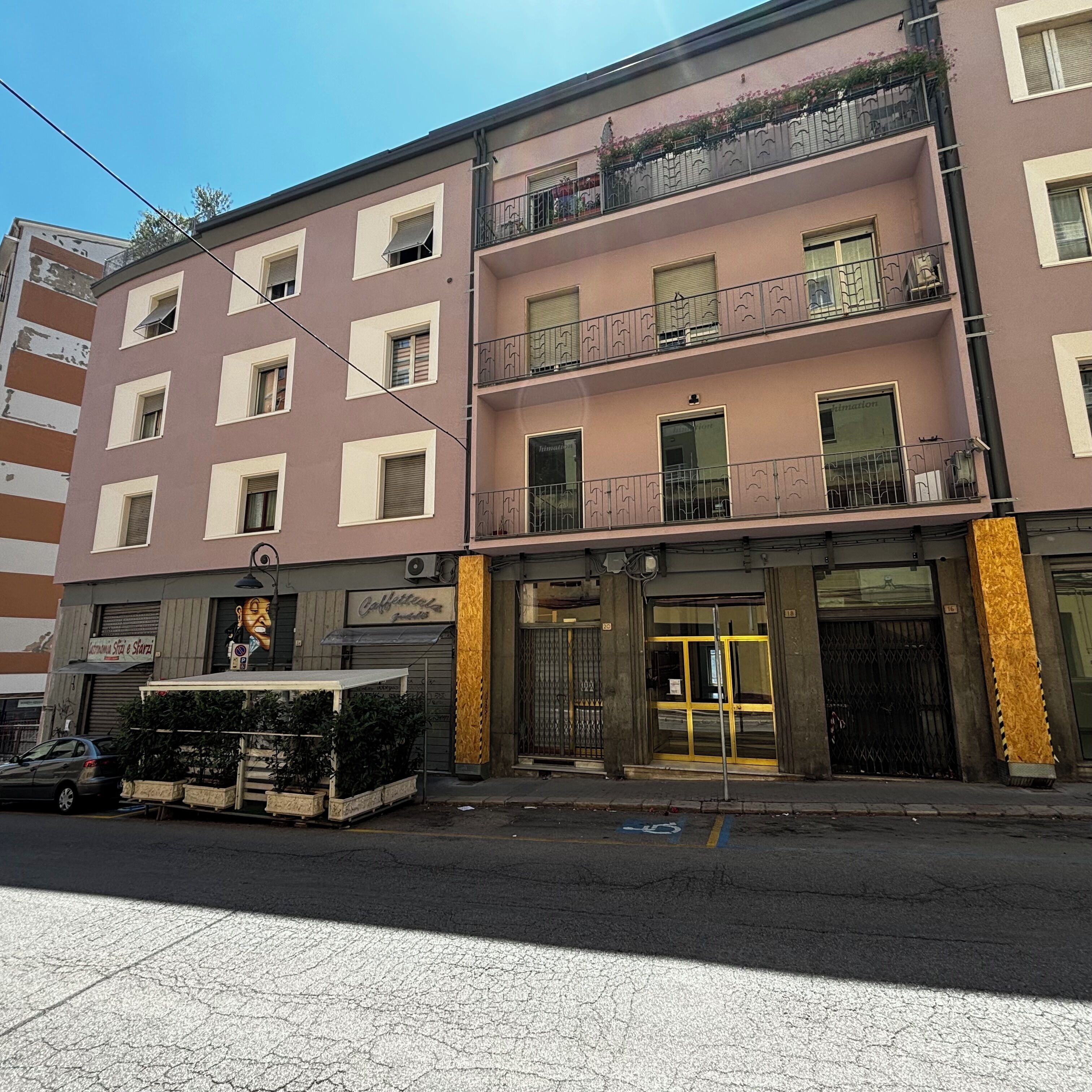 A multi-story building with balconies, a ground-level shop, and a gated entrance.