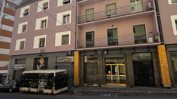 A multi-story building with balconies, a ground-level shop, and a gated entrance.