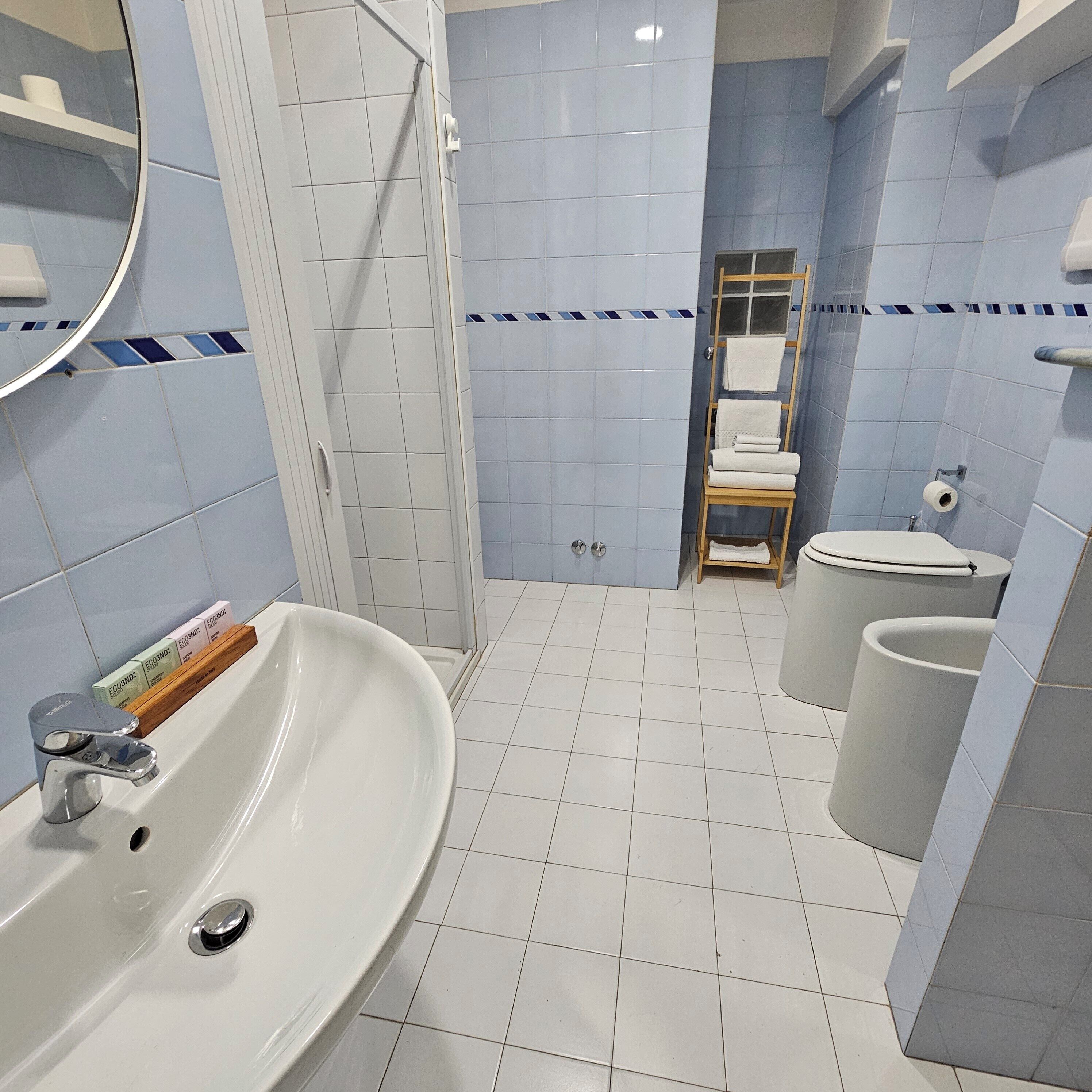 Un baño con lavamanos blanco, inodoro y zona de ducha.