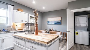 Una cocina moderna con armarios blancos, una isla de madera y un lavavajillas integrado.