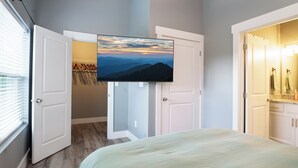 Un dormitorio con cama, televisor montado en la pared y armario con espejo.