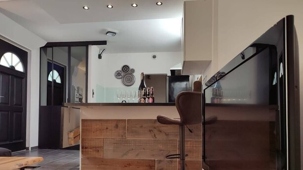 A modern kitchen with a wooden island, a bar area, and a large flat-screen TV. - Rêve de Bulles, 62m2 of charm, 2 large bedrooms (Châlons-en-Champagne)