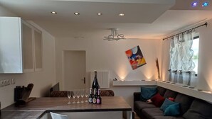 A modern kitchen with a dining area, a sofa with cushions, and a wine bottle on the counter. - Rêve de Bulles, 62m2 of charm, 2 large bedrooms (Châlons-en-Champagne)