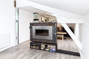 A compact, rustic wood-burning stove in a modern loft bedroom with a sloped ceiling and a view of the living area. - 3 bedrooms and the Moon Terrace 103m2 of charm (Châlons-en-Champagne)
