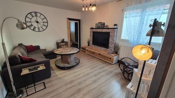 A living room with a sofa, a coffee table, a TV, and a fireplace.
