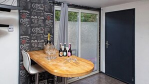 A small dining area with a wooden table, a white chair, and a menu wall.
